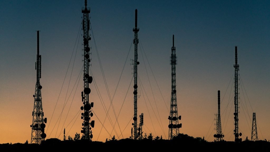 Silhouetted telecom towers and antennas at dusk, the radio access network layer AI-RAN aims to transform